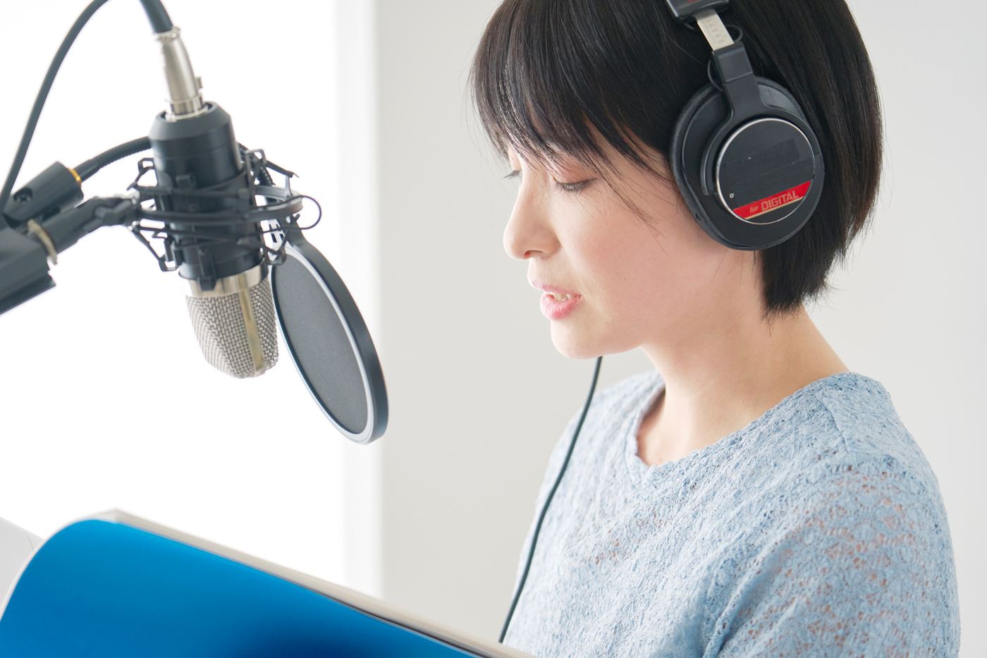A narrator in headphones reading a script into a studio microphone