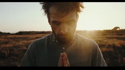 A man praying in a field at sunset